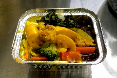  A small to-go box of barbequed soy chunks with pineapple, curried squash and carrots, mixed veggie noodles, and sautéed greens